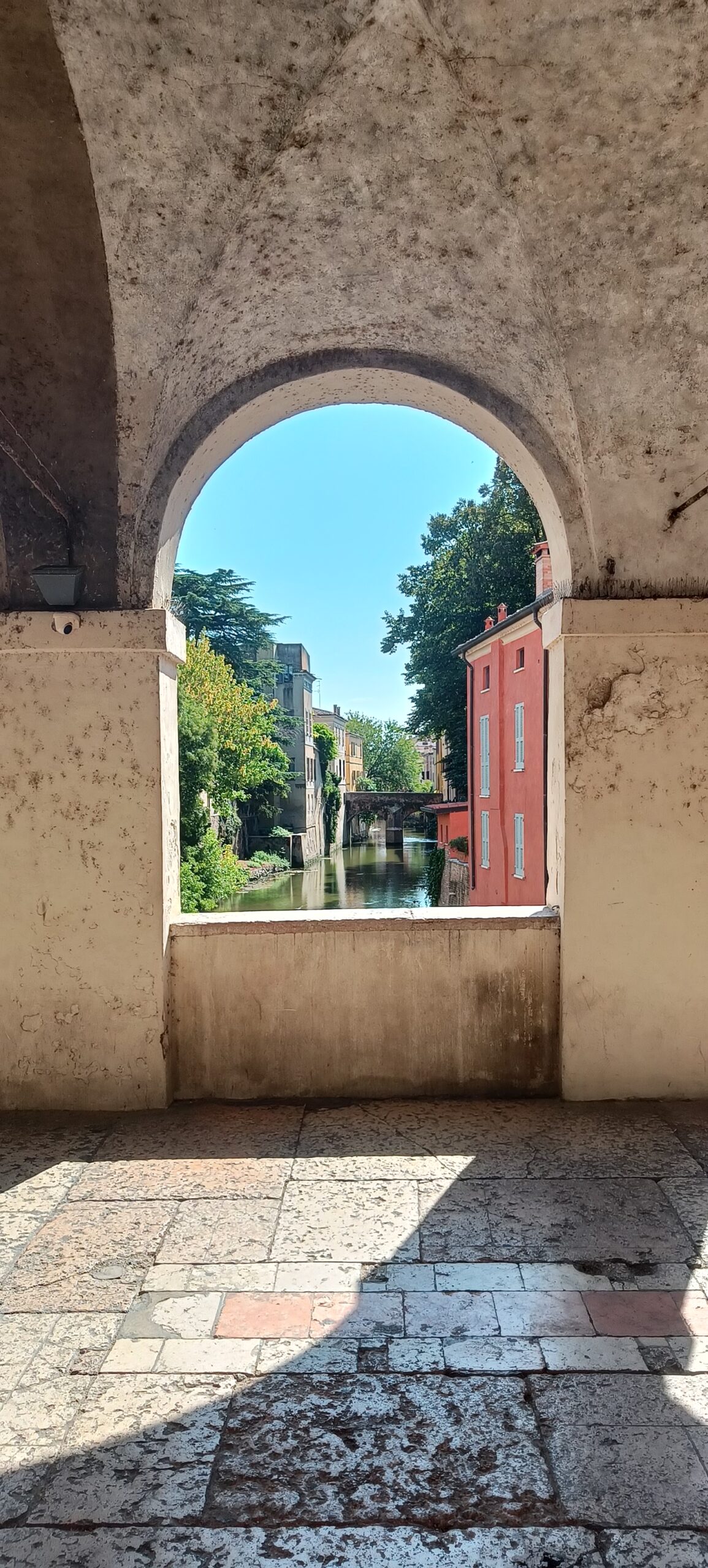 Mantua mit dem Wohnmobil – unsere erste Etappe zwischen Seen, alten Mauern und großen Geschichten Blick durch einen steinernen Rundbogen auf einen Wasserlauf und die Häuser von Mantua